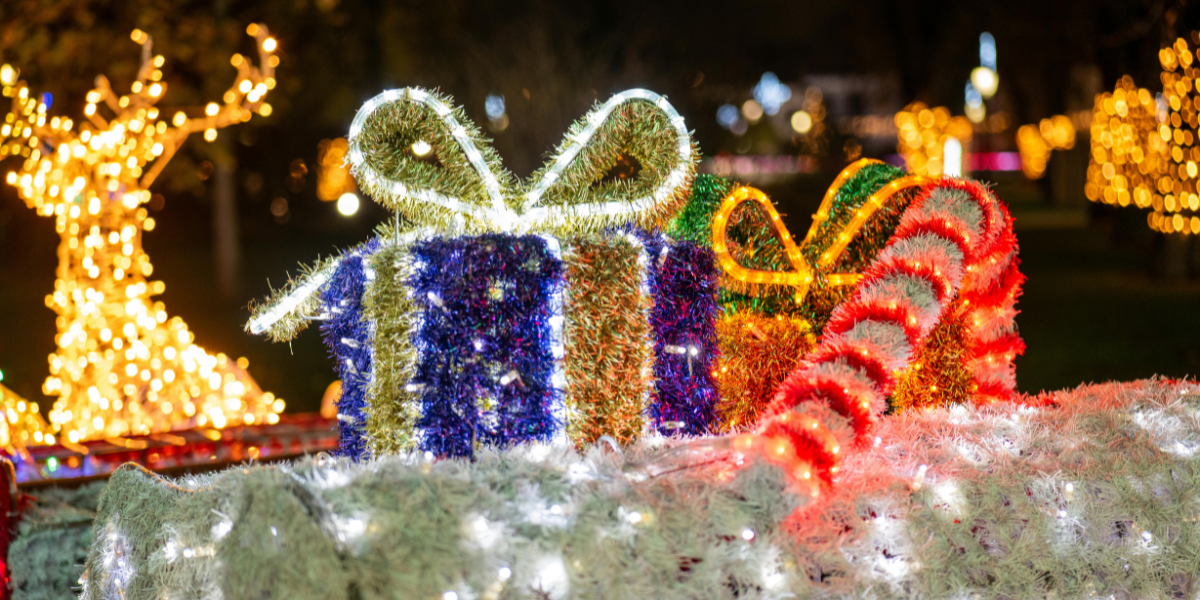 Colorful holiday gift boxes adorned with lights and festive decorations, surrounded by glowing holiday lights in a nighttime outdoor setting, representing outdoor holiday lighting ideas.